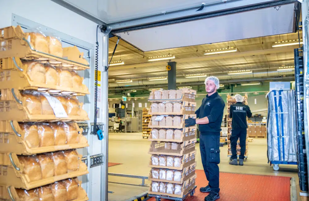 Medewerker van HR Transport & Logistiek laadt kratten met brood in een vrachtwagen